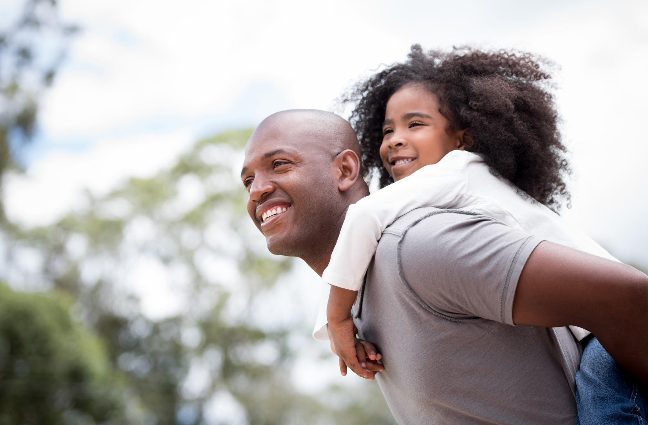 Happy black father playing with his daughter outdoors